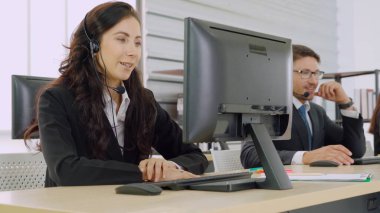 Ofiste çalışan kulaklık takan işadamları uzak müşteri ya da meslektaşlarını desteklemek için çalışıyorlar. Arama merkezi, tele pazarlama, müşteri destek acentesi telefon görüşmesinde hizmet sunar.