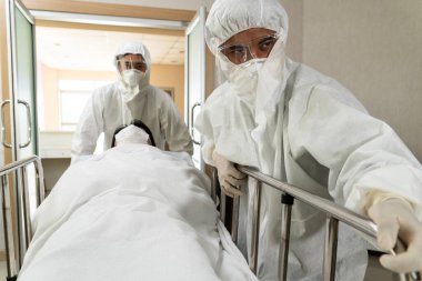 Acil servis doktoru ve doktor hastayı hastanedeki acil servise götürüyor. Doktor koronavirüs ve covid 19 koruma ve karantina kavramında koruyucu giysi ve yüz maskesi takıyor. .
