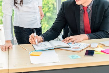 İki iş adamı toplantı odasında proje stratejisi hakkında konuşuyor. İş adamı, mali veri raporu hakkında sohbet ve tavsiyelerde bulunurken, modern işyerindeki iş arkadaşıyla proje planlamasını tartıştı.