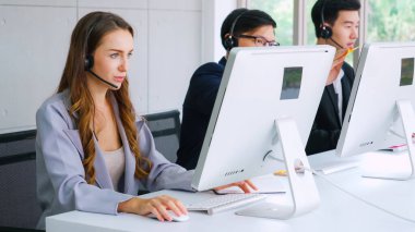 Ofiste çalışan kulaklık takan işadamları uzak müşteri ya da meslektaşlarını desteklemek için çalışıyorlar. Arama merkezi, tele pazarlama, müşteri destek acentesi telefon görüşmesinde hizmet sunar.