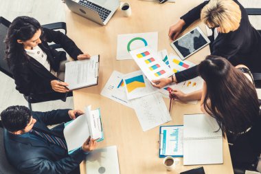 İş adamları grup toplantısı ofiste yukarıdan çekildi. İş kadınları, iş adamları ve ofis çalışanları, proje planlama belgeleriyle takım konferansında toplantı masasında çalışıyorlar. .