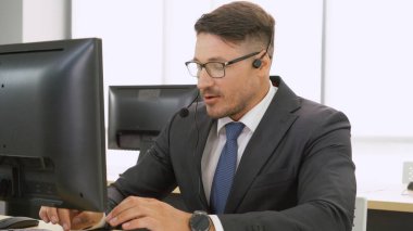 Ofiste çalışan kulaklık takan işadamları uzak müşteri ya da meslektaşlarını desteklemek için çalışıyorlar. Arama merkezi, tele pazarlama, müşteri destek acentesi telefon görüşmesinde hizmet sunar.