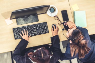 Ofiste üst kademeden kulaklık takan işadamları uzak müşteri ya da meslektaşlarını desteklemek için bilgisayarla çalışıyorlar. Çağrı merkezi, tele pazarlama acente servisi telefon ya da video konferans çağrısı.