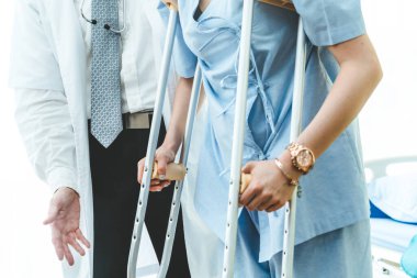 Doktor hastanede koltuk değnekli hastayla ilgileniyor. Fizyoterapist ve bacak yaralanması konsepti.