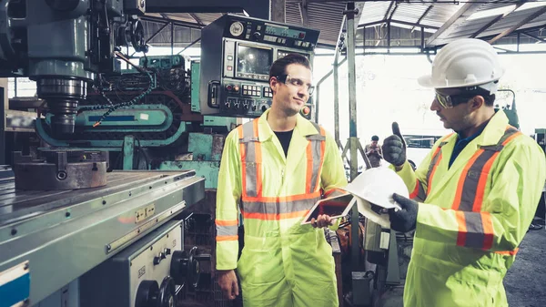 Factory worker warn coworker about safety and give hardhat to him . Injury prevention and safety first concept .