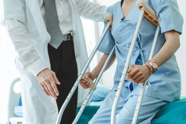Doktor hastanede koltuk değnekli hastayla ilgileniyor. Fizyoterapist ve bacak yaralanması konsepti.