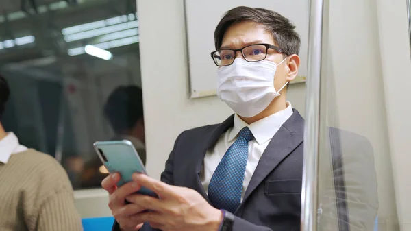 Reisender trägt Gesichtsmaske bei Handynutzung in S-Bahn — Stockfoto
