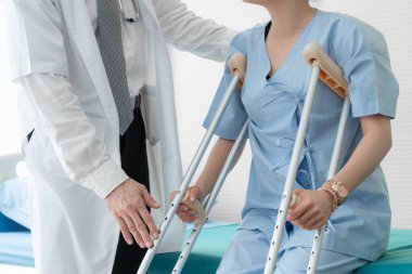 Doktor hastanede koltuk değnekli hastayla ilgileniyor.