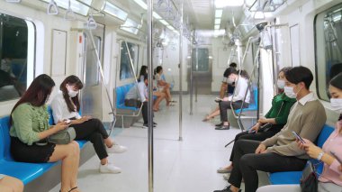 Kalabalık bir metroda maske takan insanlar.