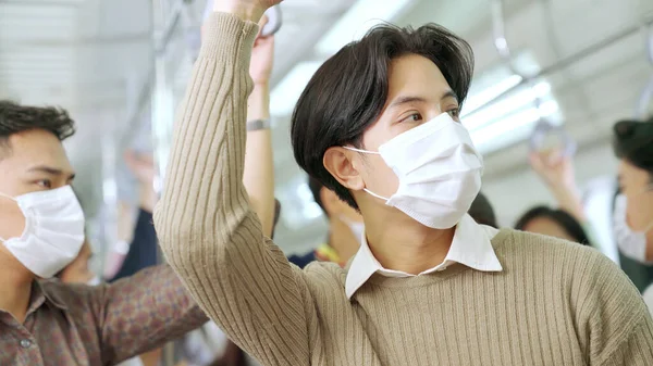 Young man wearing face mask travels on crowded subway train