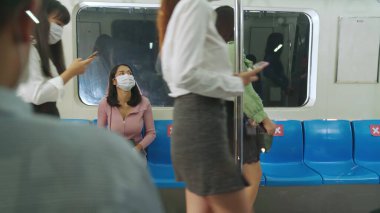 Kalabalık bir metroda maske takan insanlar.