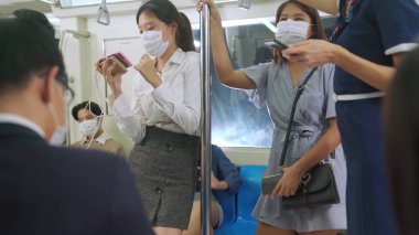 Kalabalık bir metroda maske takan insanlar.