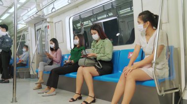 Kalabalık bir metroda maske takan insanlar.