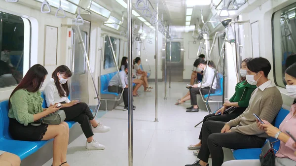 Kalabalık bir metroda maske takan insanlar.