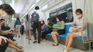 Kalabalık bir metroda maske takan insanlar.