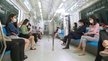 Kalabalık bir metroda maske takan insanlar.