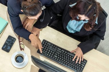 Ofiste kulaklık takan iş adamları bilgisayarla çalışıyorlar.