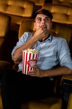 Gülümseyen genç bir adam film izlemekten hoşlanıyor.