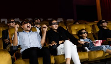 Sinema salonunda 3 boyutlu film izleyen bir grup insan.