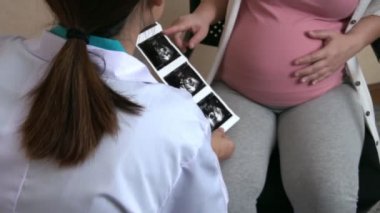Mutlu hamile kadın, jinekolog doktoru hastanede ya da klinikte hamilelik danışmanlığı için ziyaret ediyor. Doktor, bebek ve anne sağlığı kontrolü için hamile karnı muayene ediyor. Jinekoloji konsepti.