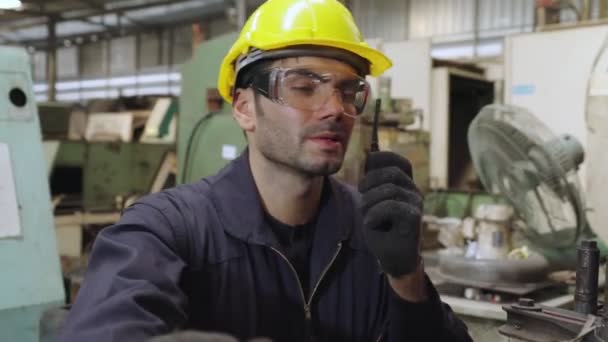 Fabrieksarbeider praat op draagbare radio tijdens inspectie van machineonderdelen — Stockvideo