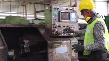 Fabrika işçisi fabrika atölyesinde makine teçhizatı kullanmayı öğretiyor.