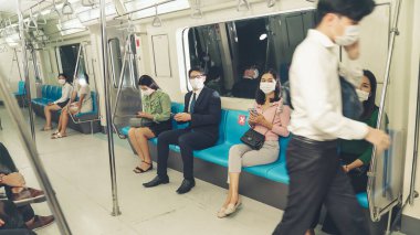 Kalabalık bir metroda maske takan insanlar.