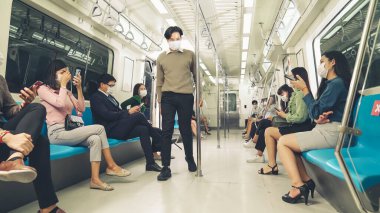Kalabalık bir metroda maske takan insanlar.
