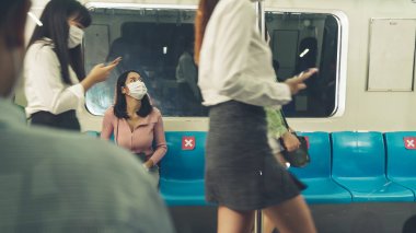 Kalabalık bir metroda maske takan insanlar.
