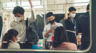 Kalabalık bir metroda maske takan insanlar.