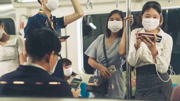 Kalabalık bir metroda maske takan insanlar.