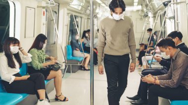 Kalabalık bir metroda maske takan insanlar.