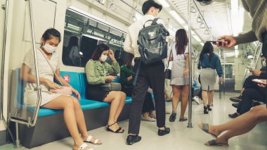 Kalabalık bir metroda maske takan insanlar.