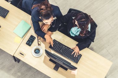 Ofiste kulaklık takan iş adamları bilgisayarla çalışıyorlar.