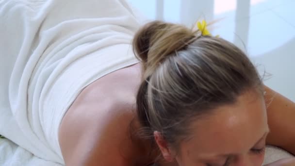 Rahatlamış genç bir kadın masaj için spa yatağında yatıyor.. — Stok video