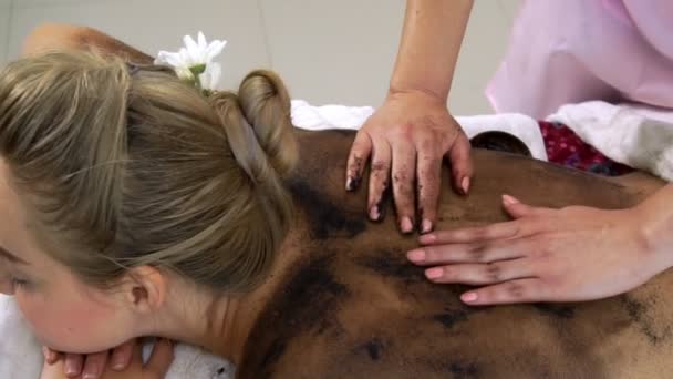 Ontspannen vrouw liggend op spa bed voor lichaam schrobben massage met behulp van traditionele kruid — Stockvideo