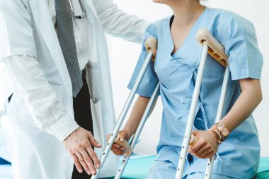 Doktor hastanede koltuk değnekli hastayla ilgileniyor.