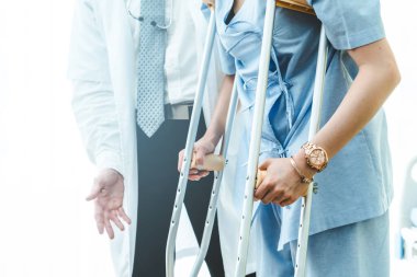 Doktor hastanede koltuk değnekli hastayla ilgileniyor.