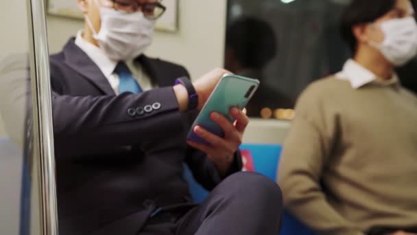 Ταξιδιώτης με μάσκα προσώπου κατά τη χρήση κινητού τηλεφώνου σε δημόσιο τρένο — Αρχείο Βίντεο
