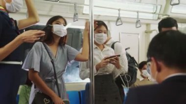Kalabalık bir metroda maske takan insanlar.