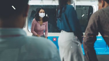 Kalabalık bir metroda maske takan insanlar.