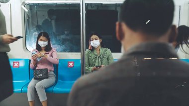 Kalabalık bir metroda maske takan insanlar.