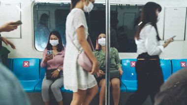 Kalabalık bir metroda maske takan insanlar.