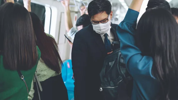 Молодой человек в маске путешествует в переполненном поезде метро — стоковое фото