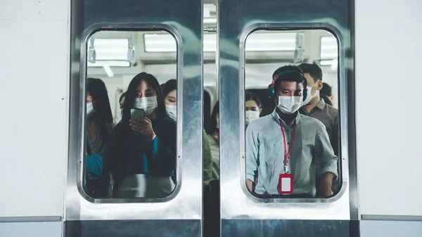 Multitud de personas que usan mascarilla facial en un concurrido tren público de metro — Foto de Stock