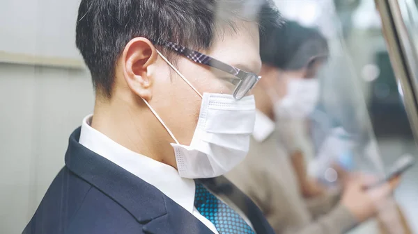 Junger Mann mit Gesichtsmaske fährt in überfüllter U-Bahn — Stockfoto
