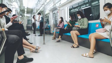 Kalabalık bir metroda maske takan insanlar.