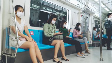 Kalabalık bir metroda maske takan insanlar.