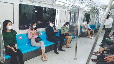 Kalabalık bir metroda maske takan insanlar.