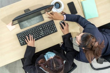Ofiste kulaklık takan iş adamları bilgisayarla çalışıyorlar.